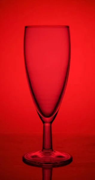 Άδειο γυάλινο ποτήρι σαμπάνιας στον αυλό σε κόκκινο φόντο — Φωτογραφία Αρχείου
