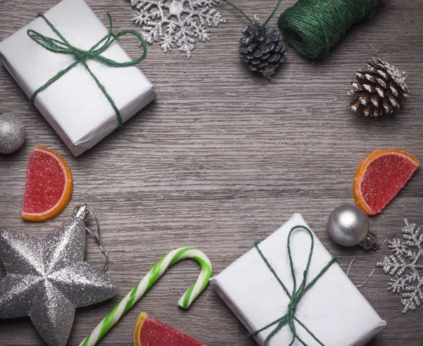 Deux cadeaux enveloppés dans du papier blanc pour Noël avec des décorations et des bonbons et avec une copie de l'espace sur un fond en bois — Photo