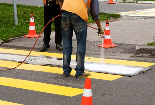 Yol işçileri, şablonda beyaz boya püskürten yeni bir yaya geçidi yarattılar..
