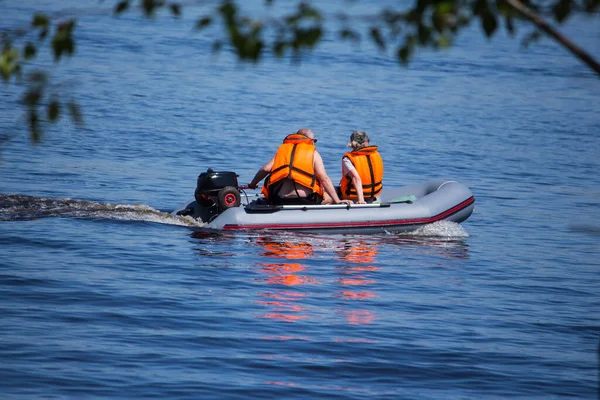 a couple a woman and a man ride on an inflatable boat with a motor.