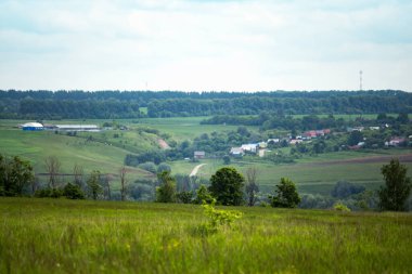 arazi, bulutlu gökyüzü uzak bir Rus yeşil köyü üzerinde.