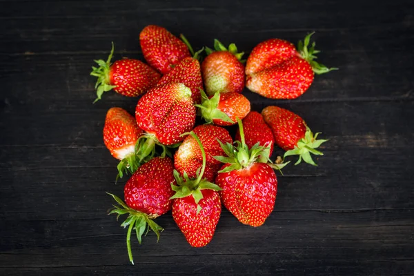 red ripe strawberries on a black wooden background top view.