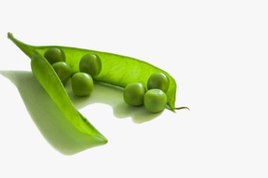 Beyaz bir zemin üzerinde yeşil bir bezelye kabuğunda olgun bezelyeler..