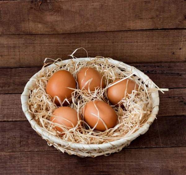 Kahverengi ahşap arka planda kahverengi yumurtaları olan hasır tahta bir tabak..