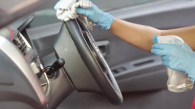 Arabanın içini temizlemek ve dezenfeksiyon sıvısı sıkmak. Eller plastik koruyucu eldivende virüs koronası hastalığından korunmak için vihicle dezenfekte ediyor.