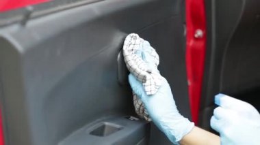 Arabanın içini temizlemek ve dezenfeksiyon sıvısı sıkmak. Eller plastik koruyucu eldivende virüs koronası hastalığından korunmak için vihicle dezenfekte ediyor.