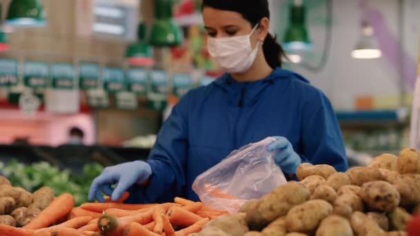 A fiatal nő orvosi maszkot és védőkesztyűt visel a Coronavirus covid-19 ellen, miközben élelmiszerboltokban vagy boltokban vásárol - egészségügyi, biztonsági és járványkitörési koncepció — Stock videók