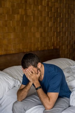 Stresli, depresif ya da kederli bir adam yatakta oturuyor, yüzünü ellerle kapatıyor ve ağlıyor. Endişeli ve hayal kırıklığına uğramış erkek depresyon ya da yaşam krizi geçiriyor. Çaresiz ve çaresiz hissediyor.
