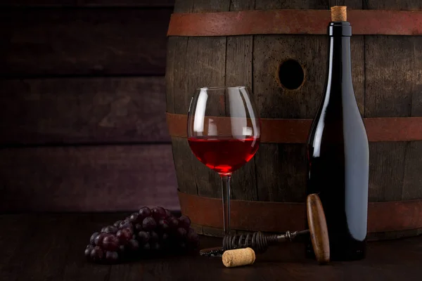 Röd vinflaska och vinglas på tunna — Stockfoto
