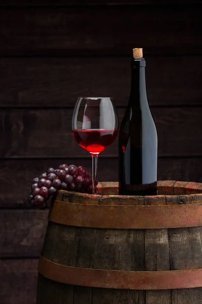 Rotweinflasche und Weinglas auf Holzfass Stockbild