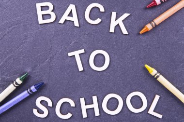 Geri okul tahtaya, tam üzerinde. İki tarafta farklı renkteki bazı mum boya kalemi.