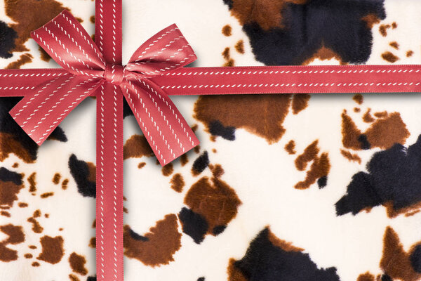 Red gift ribbon on an animal fur pattern in background. Gift box wrapping concept.