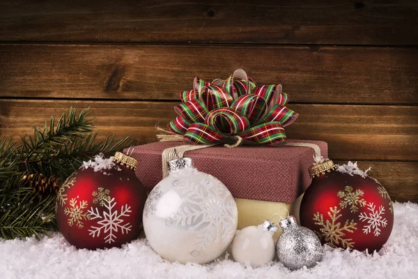 关闭在一个圣诞礼品盒与丝带和弓 装饰中的雪 和枝条 木板材在背景 — 图库照片