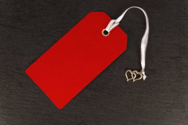 Kırmızı boş eski kağıt bez etiketi veya koyu arduvaz arka plan üzerinde izole etiket. Yakın çekim.