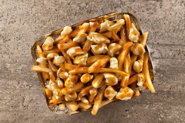 Paket servisi bir kap içinde Poutine. Kızarmış patates, sığır eti sos ve lor peyniri ile pişirilir. Kanada mutfağı.