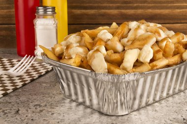 Paket servisi bir kap içinde Poutine. Kızarmış patates, sığır eti sos ve lor peyniri ile pişirilir. Kanada mutfağı.