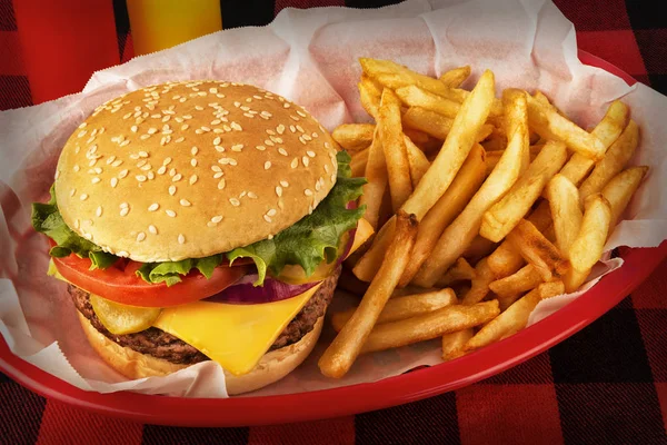 在格子呢桌布上的篮子里放的汉堡和炸薯条 背景是番茄酱和芥末瓶 — 图库照片