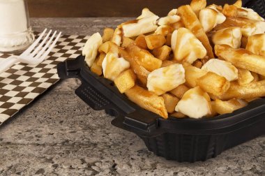 Paket servisi bir kap içinde Poutine. Kızarmış patates, sığır eti sos ve lor peyniri ile pişirilir. Kanada mutfağı.