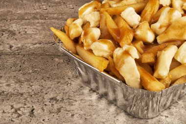 Kısmi yakın çekim yemek bir kap içinde poutine üzerinde. Kızarmış patates, sığır eti sos ve lor peyniri ile pişmiş.