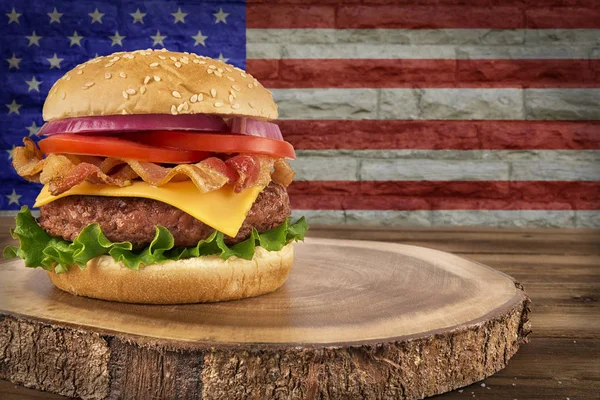 Cheeseburger with bacon. USA flag\'s on brick wall in background.