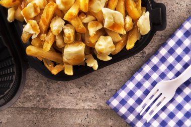 Paket servisi bir kap içinde Poutine. Kızarmış patates, sığır eti sos ve lor peyniri ile pişirilir. Kanada mutfağı.