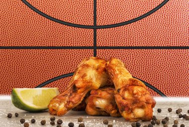 Tavuk kanadı bir limonu, tuz ve biber beton masada. Basketbol topu görüntü arka planda.