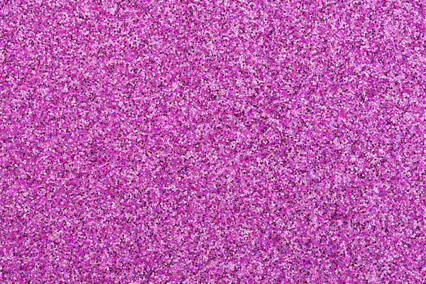 Close up on a pink glitter festive background. Sheet of pink and purple confetti. Macro.
