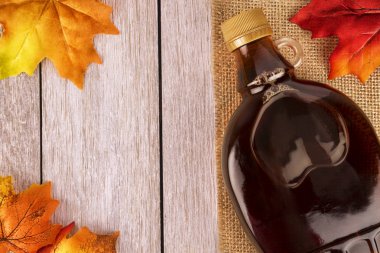 Akçaağaç şurubu şişe bir ahşap tahta üzerinde. Akçaağaç dekorasyonda bırakır. Metniniz için kopya alanı.