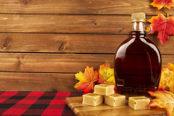 Maple syrup bottle on a wooden plank. Maple leaves in decoration. Copy space for your text.