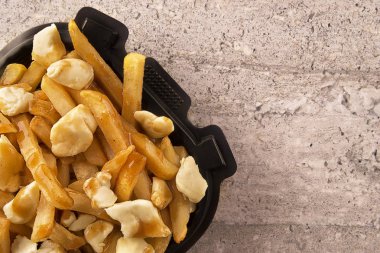 Bir paket konteyner içinde Poutine. Patates kızartması, sos lu ve lor peyniri ile pişirilir. Kanada mutfağı.