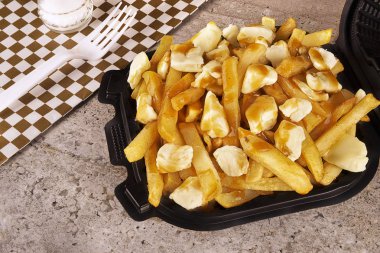 Bir paket konteyner içinde Poutine. Patates kızartması, sos lu ve lor peyniri ile pişirilir. Kanada mutfağı.