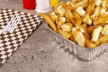 Bir paket konteyner içinde Poutine. Patates kızartması, sos lu ve lor peyniri ile pişirilir. Kanada mutfağı.