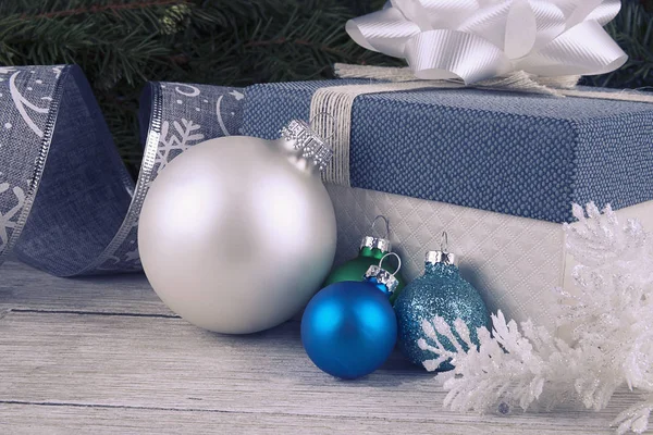 クリスマスのボーブルの装飾とリボンと白い木製の板の上にお辞儀とギフトボックス 背景にモミ — ストック写真