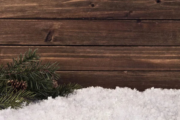 背景に天然の木製の板にクリスマスツリーの枝と雪 コピースペース付きの冬季の装飾 — ストック写真