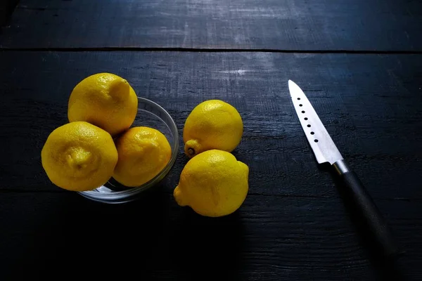 Lemons and knife on cutting board on wooden table — Stock Photo, Image