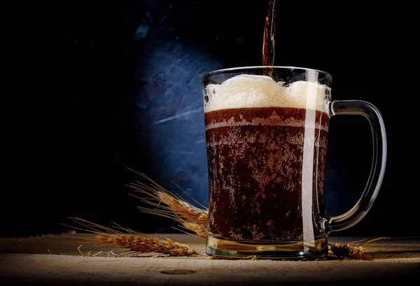 Close up of beer in glass with barley on on dark background . — Stock Photo, Image