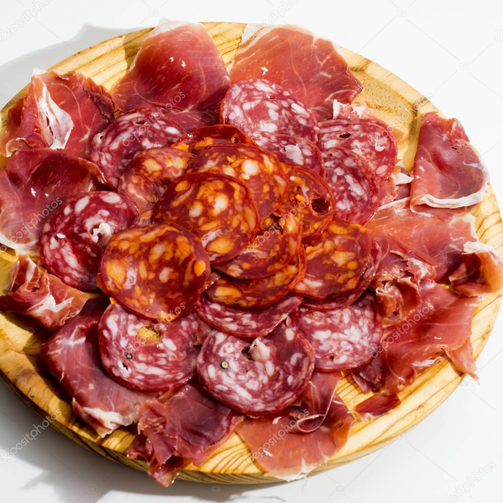 Typical spanish food with ham and sausage on a wooden plate