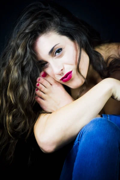 Beautiful woman with her foot near her face on black background