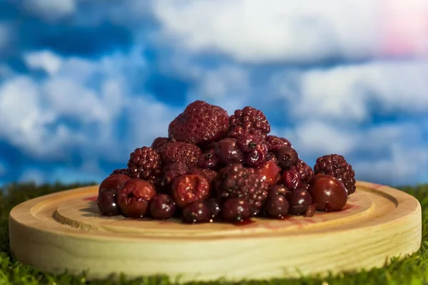 Forest fruits in a wooden dish on grass — Stock Photo, Image