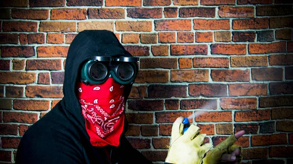 Hombre oculto con capucha y bufanda con spray en frente de una wa de ladrillo — Foto de Stock