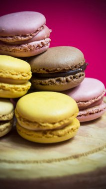 Ahşap tabakta izole edilmiş renkli makaronlar, tipik Fransız yemekleri.