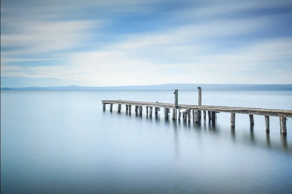 木製の桟橋か突堤は青い湖の夕日に残ります 長時間露光の写真撮影 — ストック写真