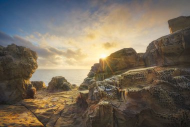 Populonia uçurumunda rüzgar ve deniz tarafından aşınmış kayalar gün batımında Buca delle Fate 'de. Piombino, Maremma Toskana, İtalya.