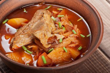 Geleneksel Ukrayna borsch kenarındaki ahşap arka plan üzerinde bir kahverengi kil kase etli.