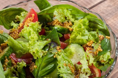 Eski ahşap arka plan üzerinde cam bir tabak yeşillik, domates ve salatalık Salatası.