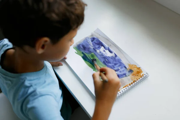 Кучерявий Темноволосий Хлопчик Синій Футболці Малює Картину Фарбами Сидячи Білим — стокове фото