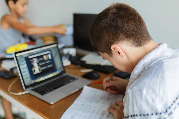 Masada oturan erkek öğrenci, uzaktan bilgisayar öğreniyor.