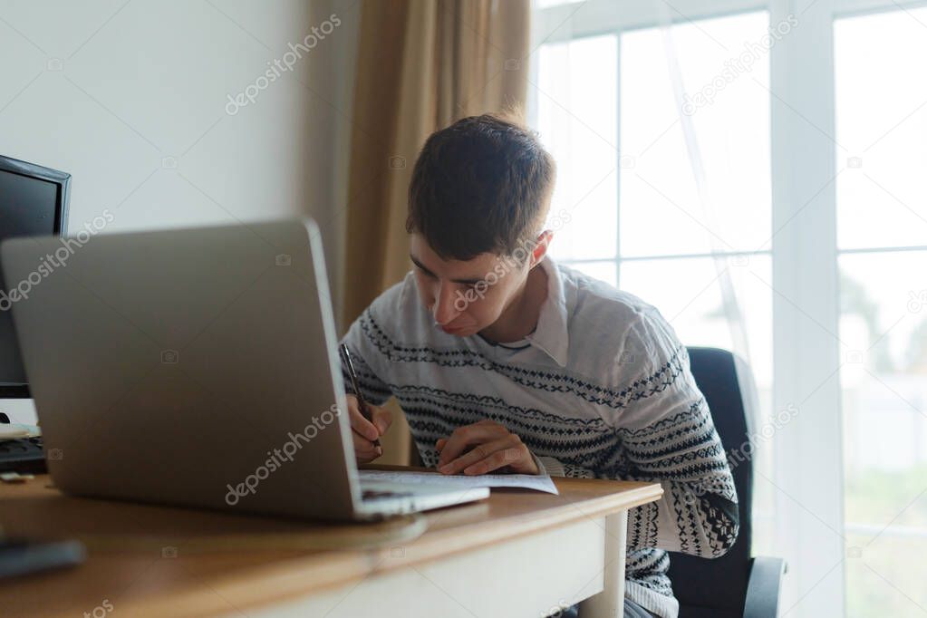 male student sitting at the table, distance learning laptop
