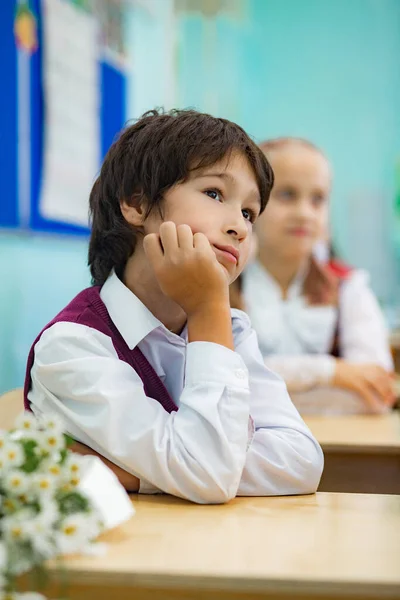 Asyalı çocuk okuldaki masasında oturuyor.