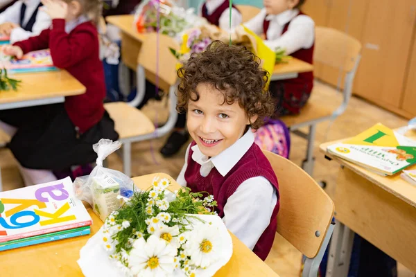 Asyalı çocuk okuldaki masasında oturuyor.